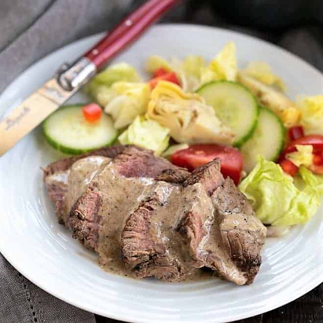 Bistrot Paul Bert Pepper Steak served on a white plate drizzled with pan sauce