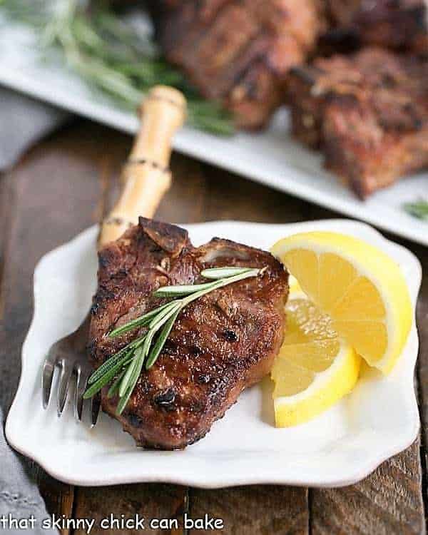 Grilled Lamb Chops with Mustard, Rosemary and Garlic on a small white plate with a sprig of rosemary and lemon wedgesGrilled Lamb Chops with Mustard, Rosemary and Garlic on a small white plate with a sprig of rosemary and lemon wedges