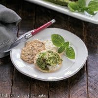 Pesto dip with crakers on a round white appetizer plate