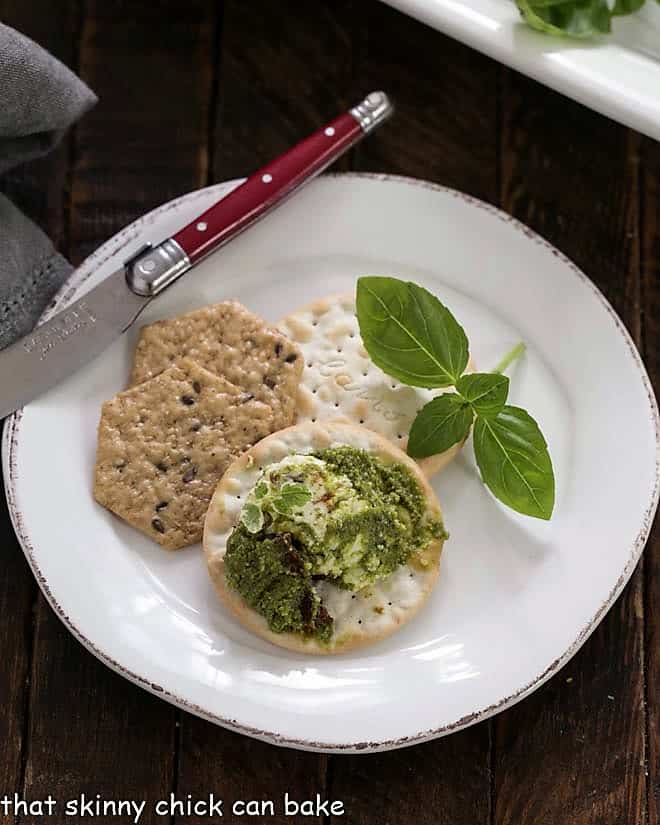 Overhead view of Layered pesto dip on a cracker on a white plate