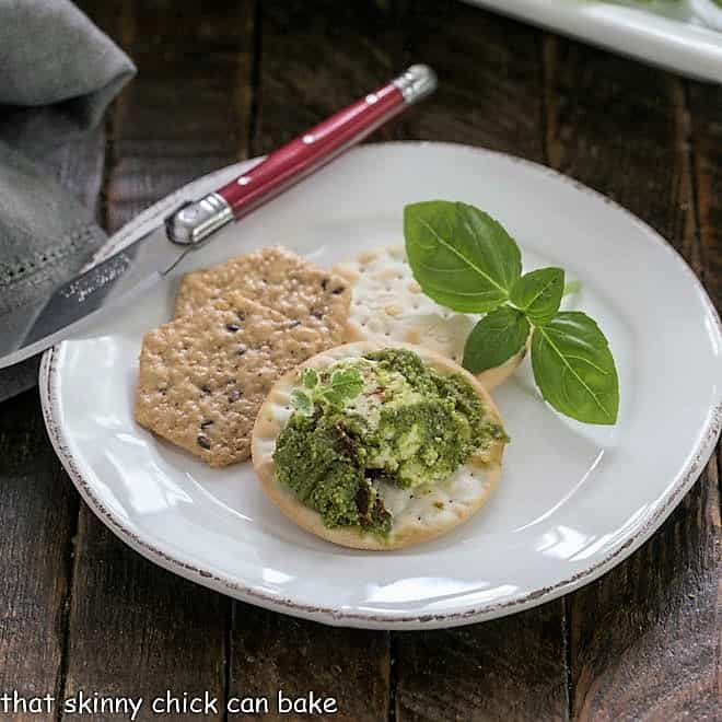 Pesto dip, crackers and fresh basil on a white plate