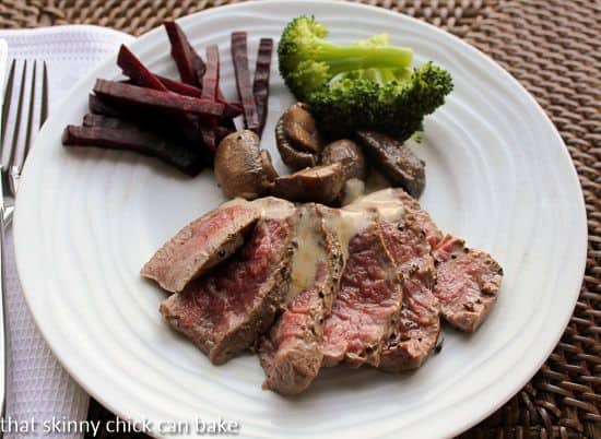 Pepper steak sliced and fanned out on a white plate and drizzled with sauce