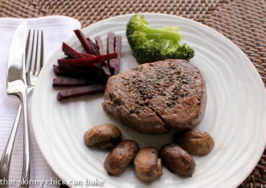 Pepper Steak on a white plate with mushrooms, beets and broccoli