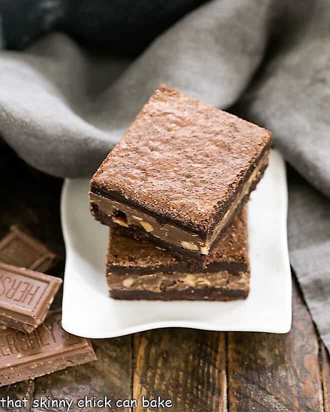 Two Symphony Toffee Brownies stacked on a square white dish.