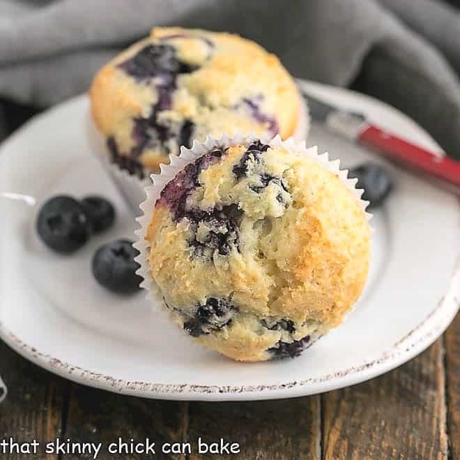 Blueberry Sour Cream Muffins on a white plate with a red handled knife.