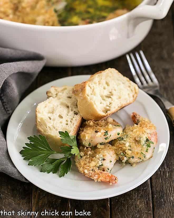 Baked Garlic Shrimp with bread on a small white plate with a bamboo handled fork