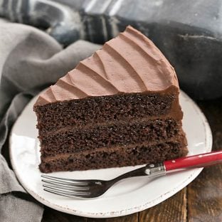 A slice of Hershey's Chocoate Cake on a white dessert plate with a red fork