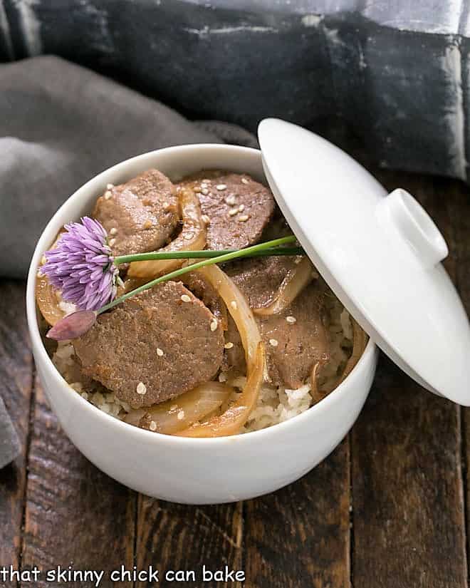 Pork Bulgoge in a white bowl over rice and garnished with chives