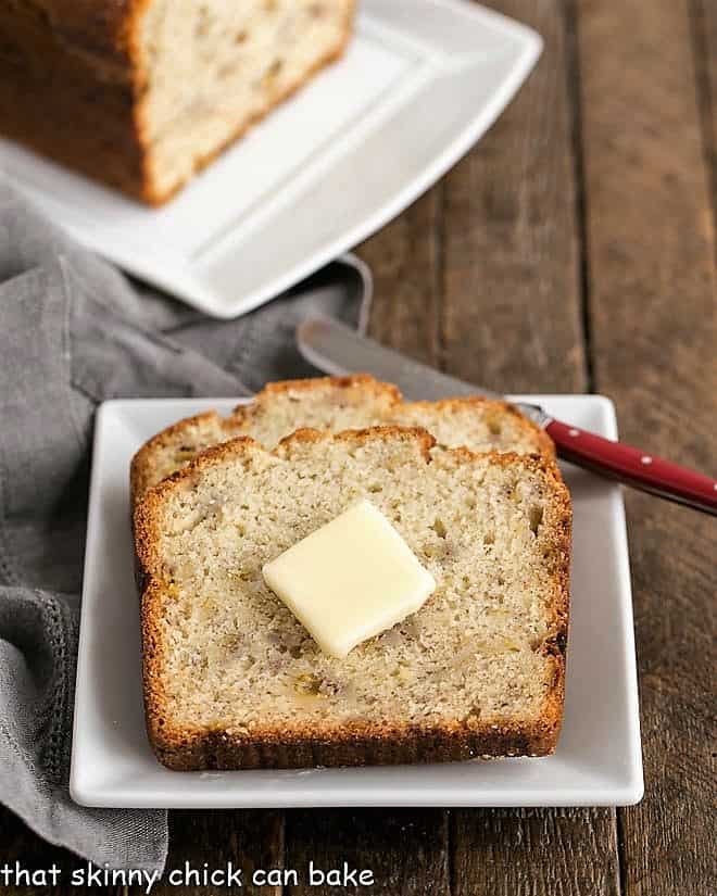 2 slices of Buttermilk Banana Bread on a square white plate topped with a pat of butter
