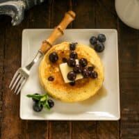 Overhead view of buttermilk pancakes with blueberries on a white plate.