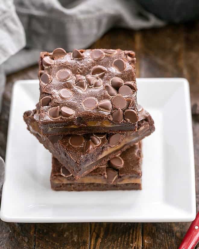 Stack of caramel brownies on a square white plate