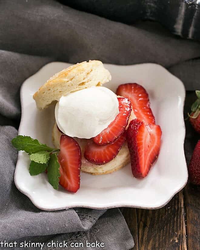 Classic Strawberry Shortcake on a square white plate with a dollop of cream and mint sprig.