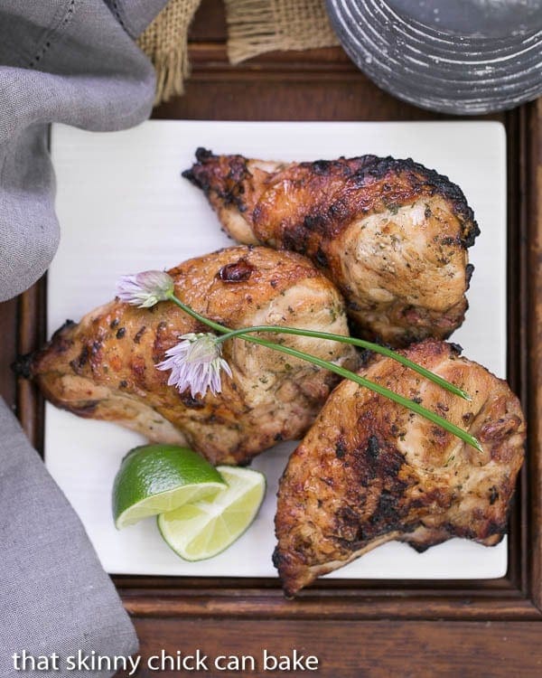 Grilled Thai Chicken on a square white plate with chive blossoms