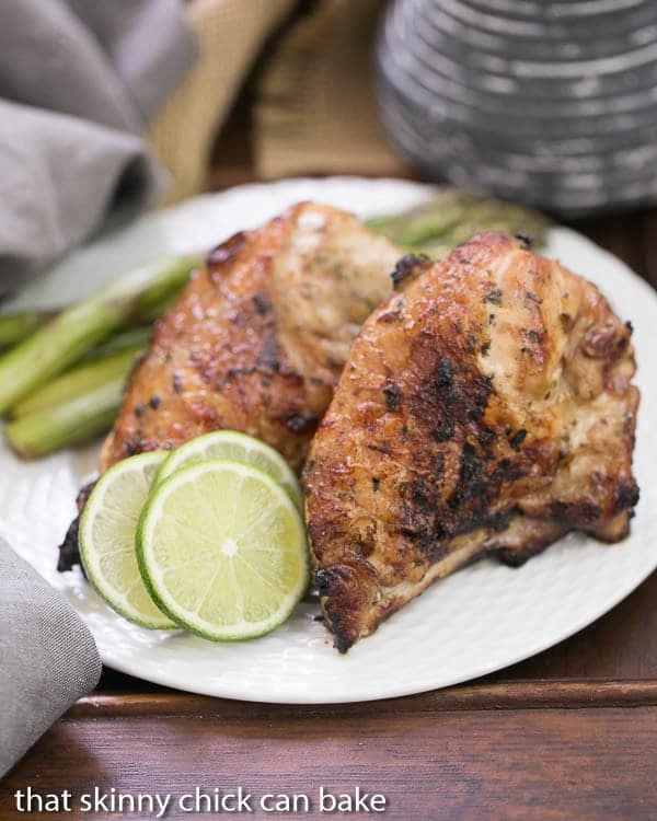 Grilled Thai Chicken on a white plate with lime slices.