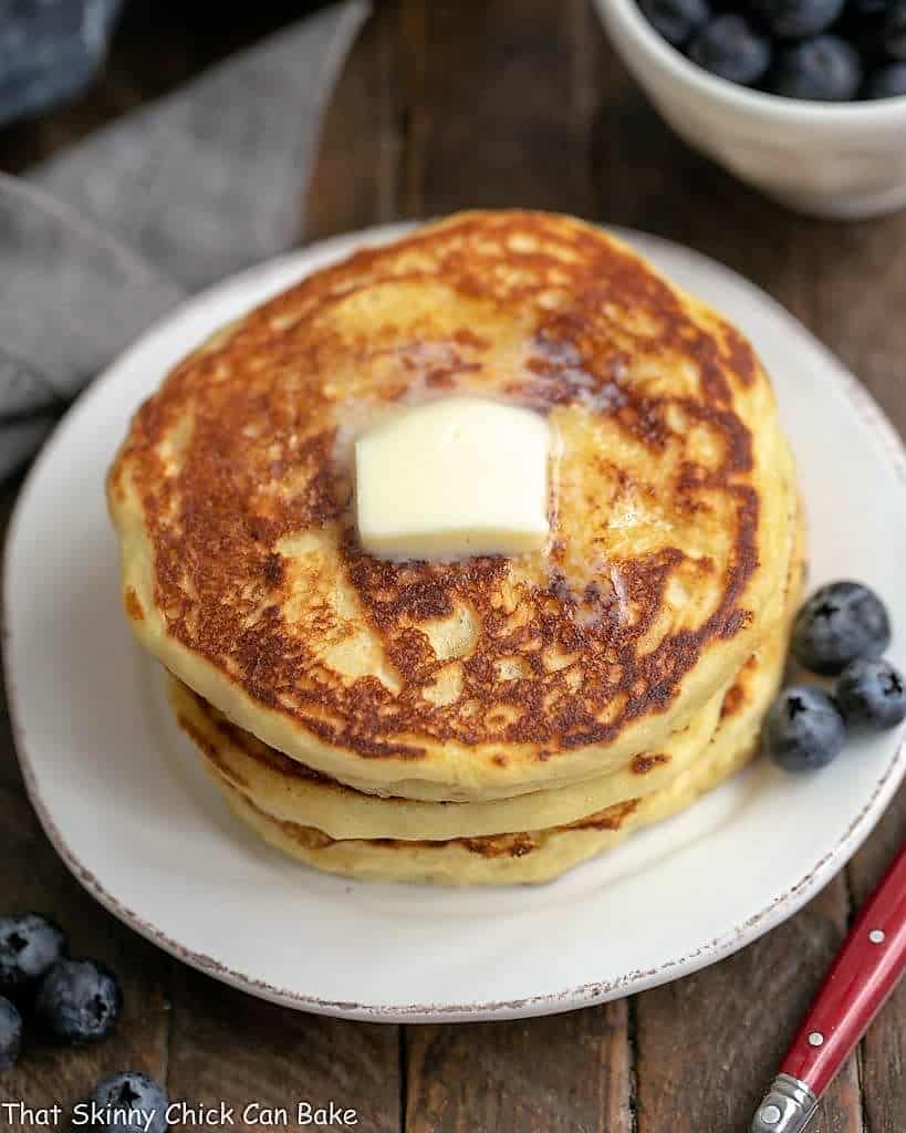 Buttermilk Pancakes with Blueberry Syrup stacked on a white plate.