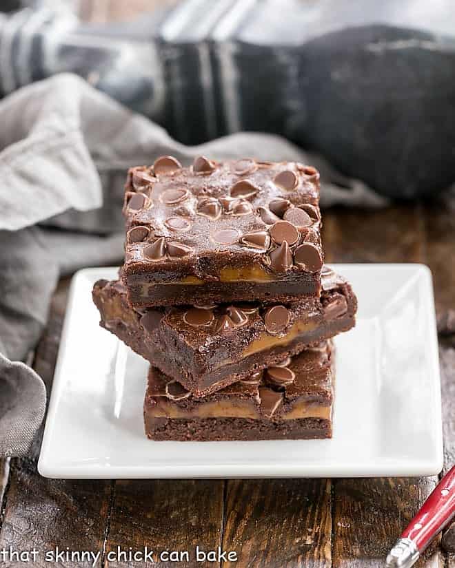 Layered caramel brownies on a square white plate.