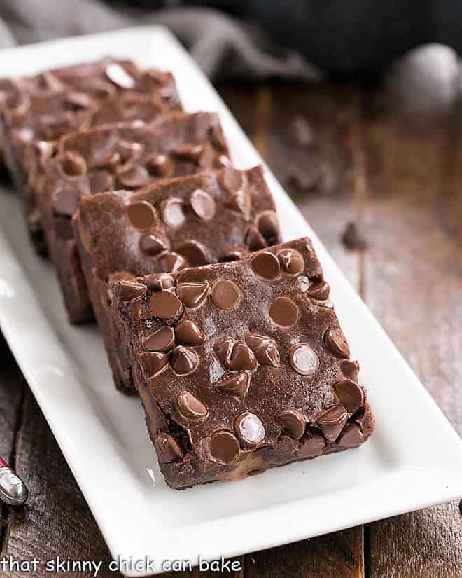 Front view of a platter of chocolate caramel brownies on a white serving tray.