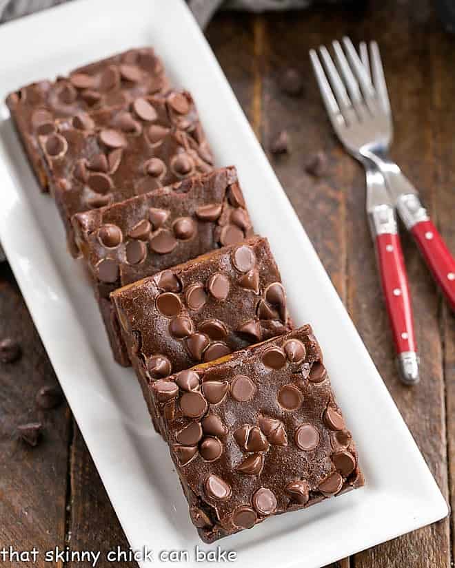 Overhead view of slices Caramel Brownies on a white rectangular tray with a couple of red handled forks 