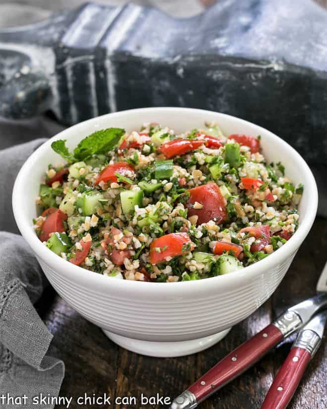 A taboouli recipe in a white serving bowl with 2 forks