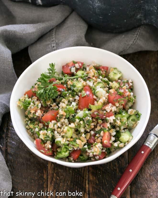 A single serving of tabouli salad in a white bowl with a fork