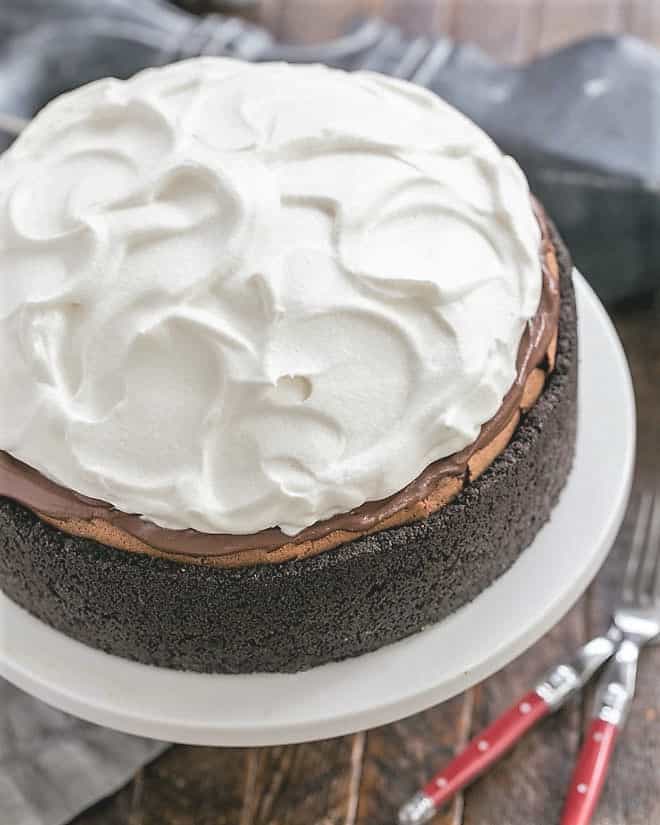 Chocolate Pudding Pie - a decadent layered dessert with an Oreo crust topped with a flourless chocolate cake, then silky chocolate pudding and whipped cream Overhead view of Oreo Mud Pie on a white cake stand.