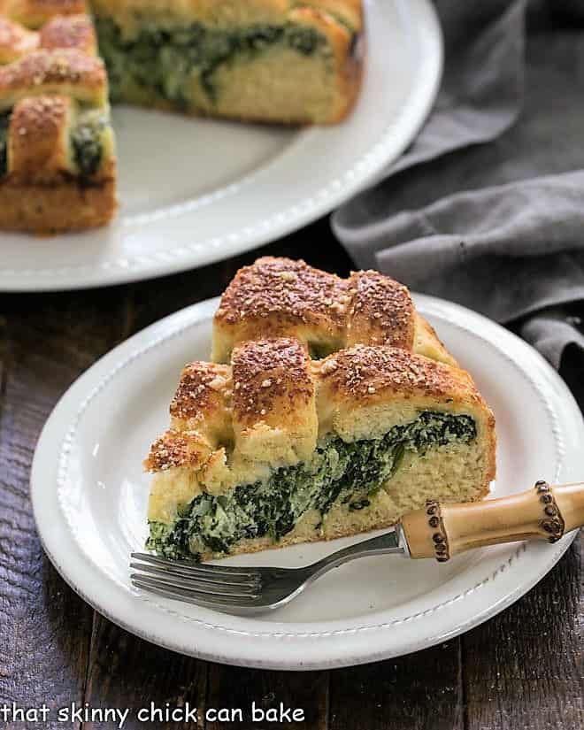 Slice of spinach tart on a white plate with a bamboo handle fork