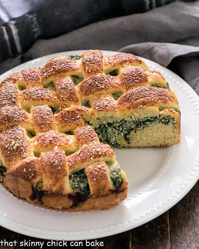 Spinach Torta Rustica with a wedge removed on a white serving plate.