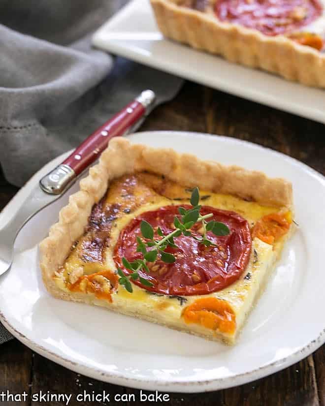 Slice of Tomato Gruyere Tart on a white plate with a red handle fork