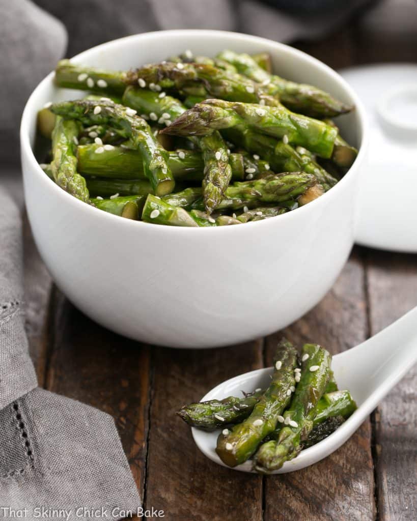 Stir fried asparagus in a white bowl and in a white Chinese soup spoon