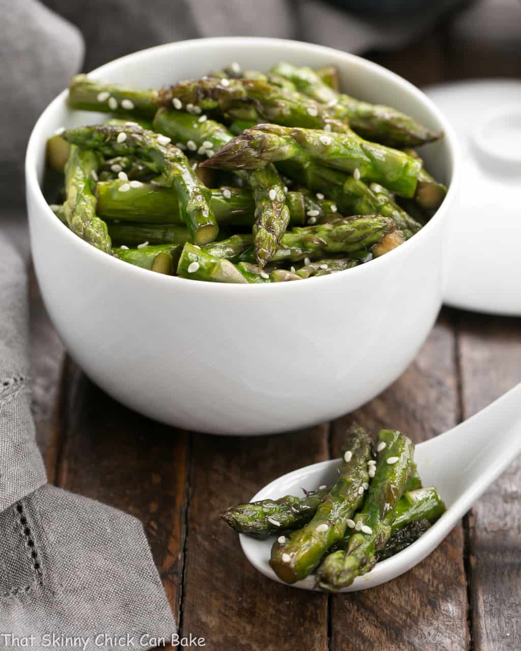 Stir fried asparagus in a white bowl and in a white Chinese soup spoon.