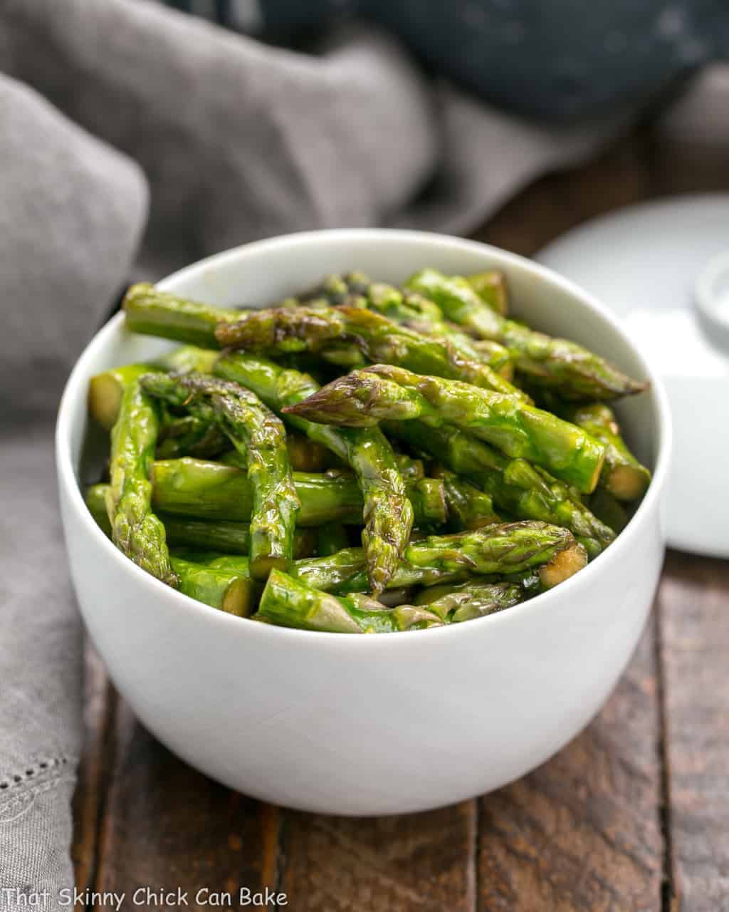 Stir fried asparagus in a white bowl.