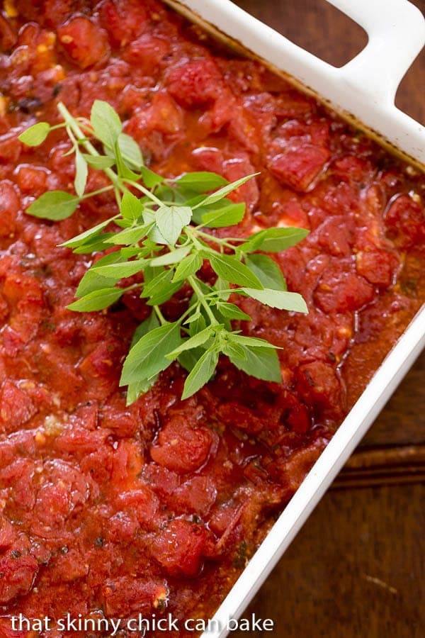 Chicken Feta Casserole in a white casserole dish with a sprig of fresh basil.