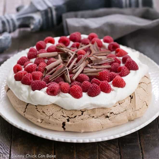 Chocolate Raspberry Pavlova on a white ceramic plate topped with cream, berries and chocolate