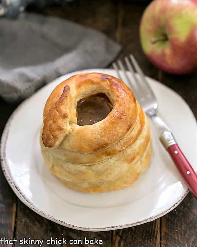 One pastry wrapped caramel apple on a round white plate