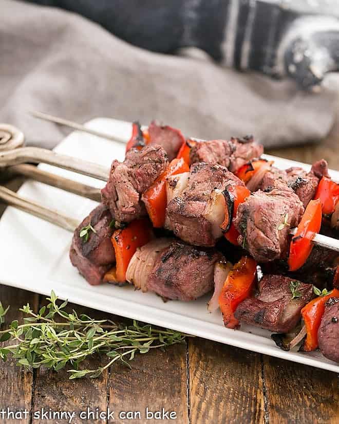 Marinated Greek Lamb Kebabs on a white serving tray with thyme garnish.