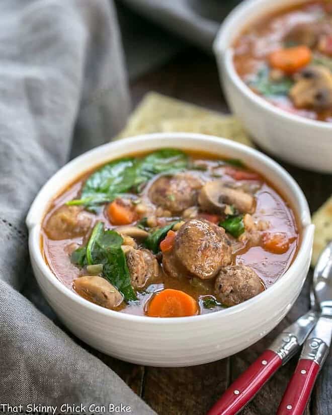 Rustic Farro Soup in two white soup bowls with spoons and crackers