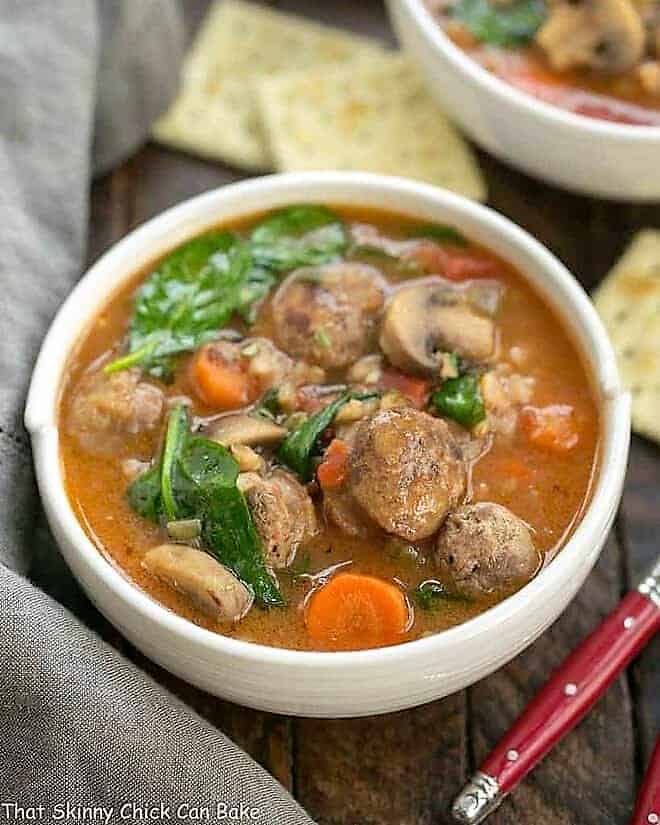 Rustic Farro Soup in a white soup bowl with a red handled spoon.