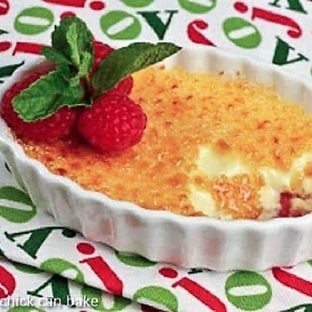 Creme brulee with raspberries in a white dish topped with fresh raspberries and mint