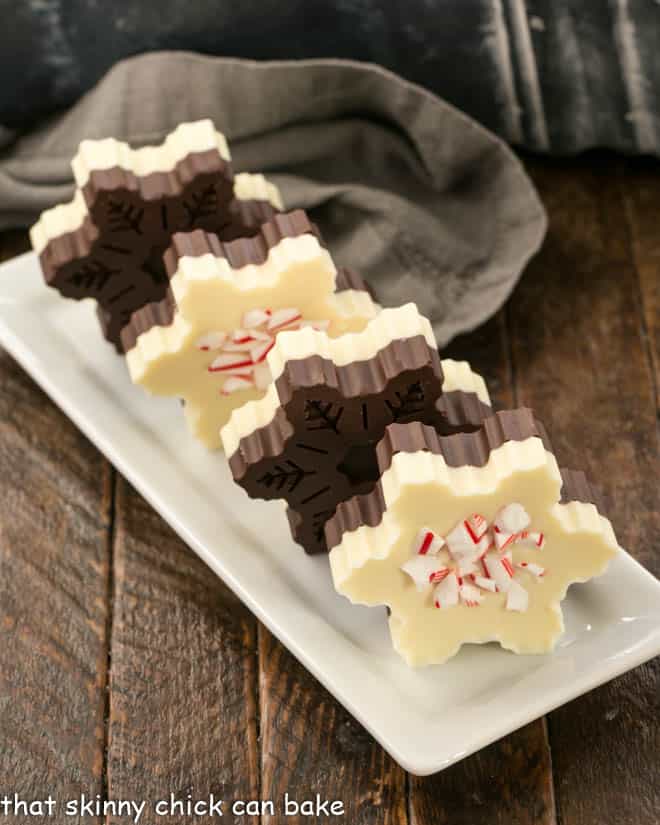 Peppermint Bark Snowflakes with candy cane shards lined up on a narrow white tray.