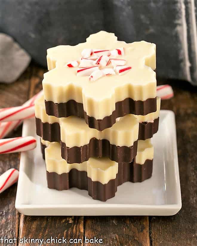 Peppermint Bark Snowflakes stacked on a white plate with candy cane garnish.