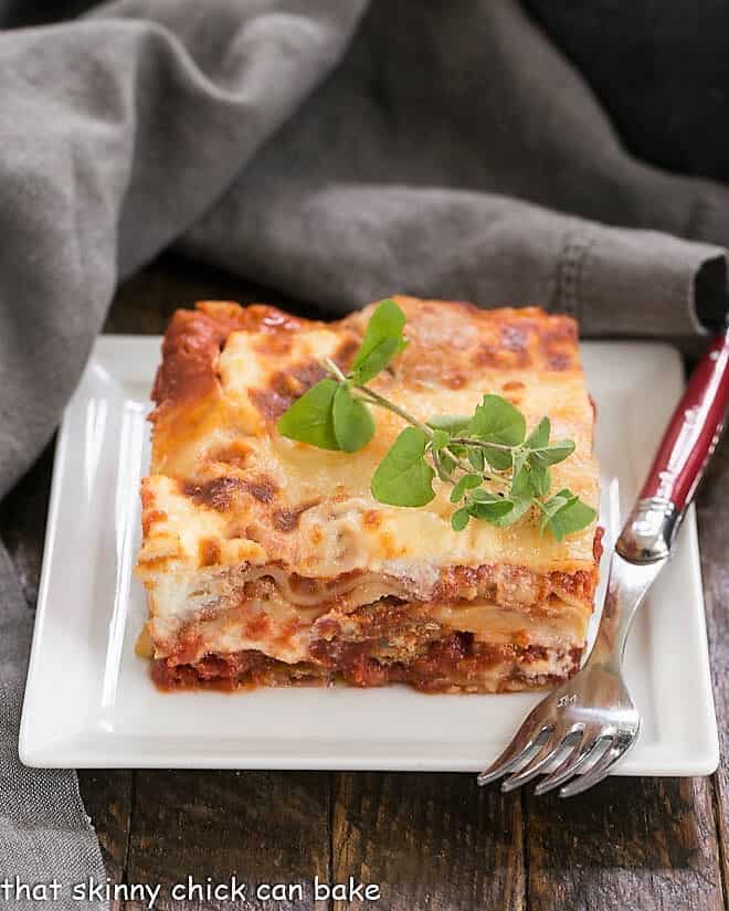 Lasagna with Italian Sausage on a white plate with a red handled fork.