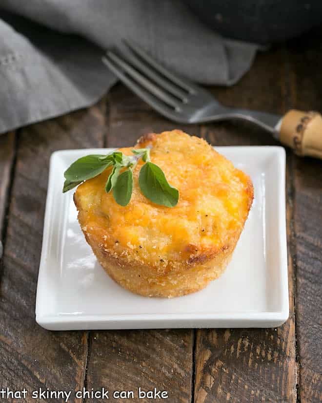 Cheesy Potato Cup on a square white plate with a sprig of herbs to garnish.