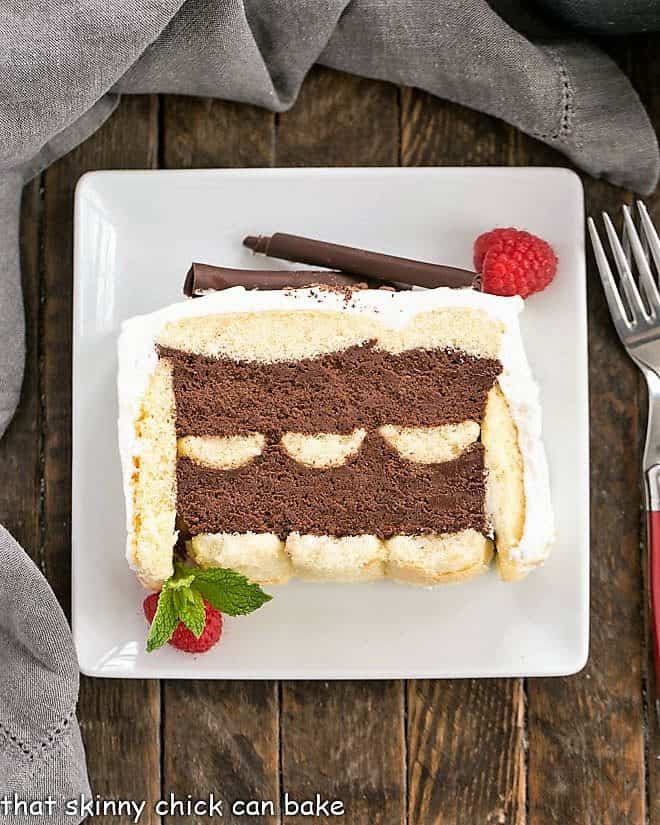 Slice of chocolate mousse cake with ladyfingers on a square white dessert plate.