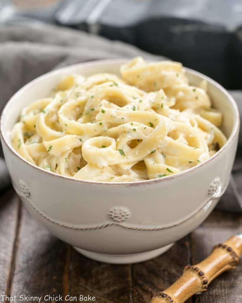 Light Fettuccine Alfredo in a white bowl garnished with parsley.