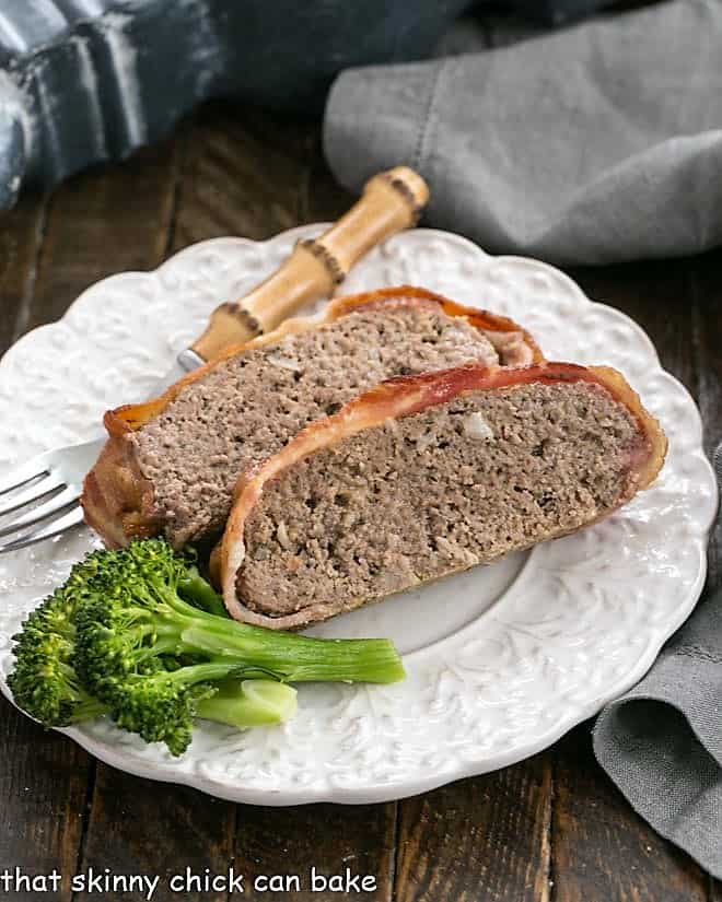 2 slices of meatloaf on a white plate with broccoli.