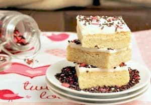 Frosted Sugar Cookie Bars stacked on 3 white plates.