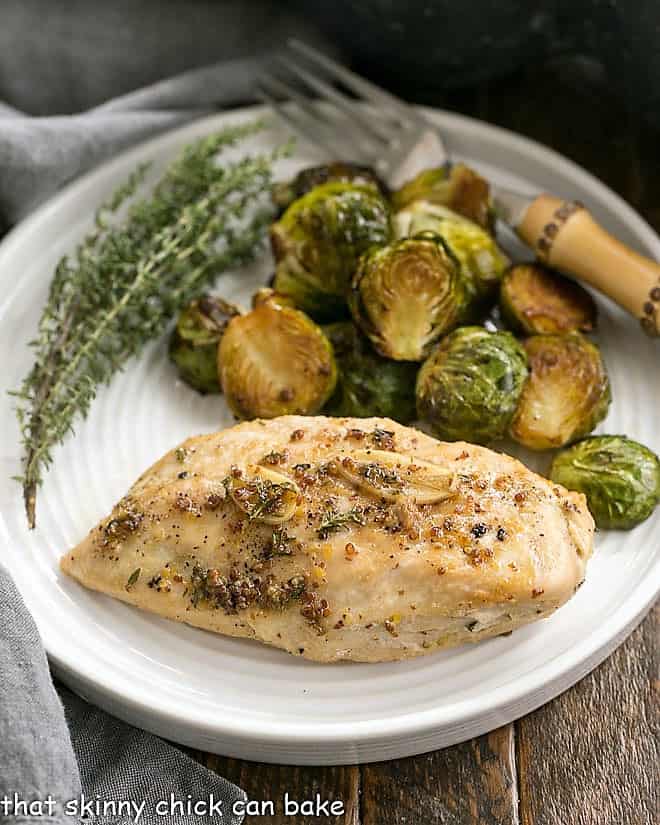 Maple-Glazed Chicken on a dinner plate with Brussels sprouts and a thyme garnish