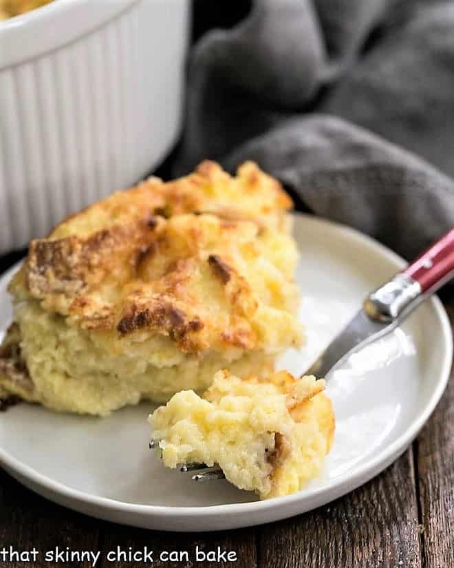 Bite of cheese souffle on a red handled fork on a plate