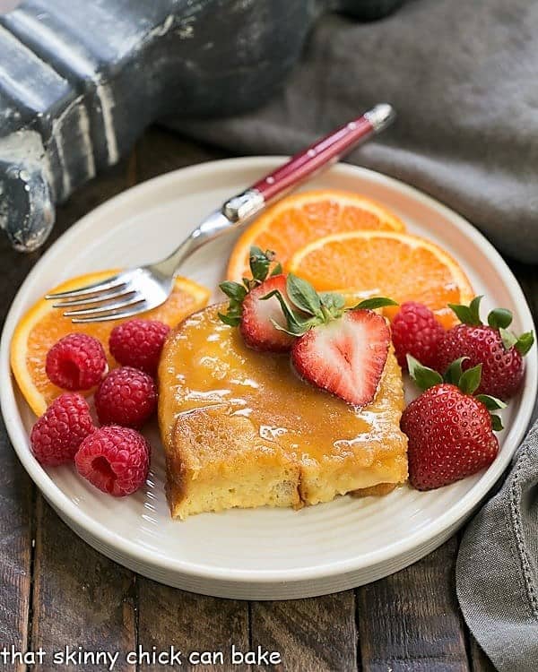 Crème Brûlée French Toast on a round plate with fruit and a red handled fork.