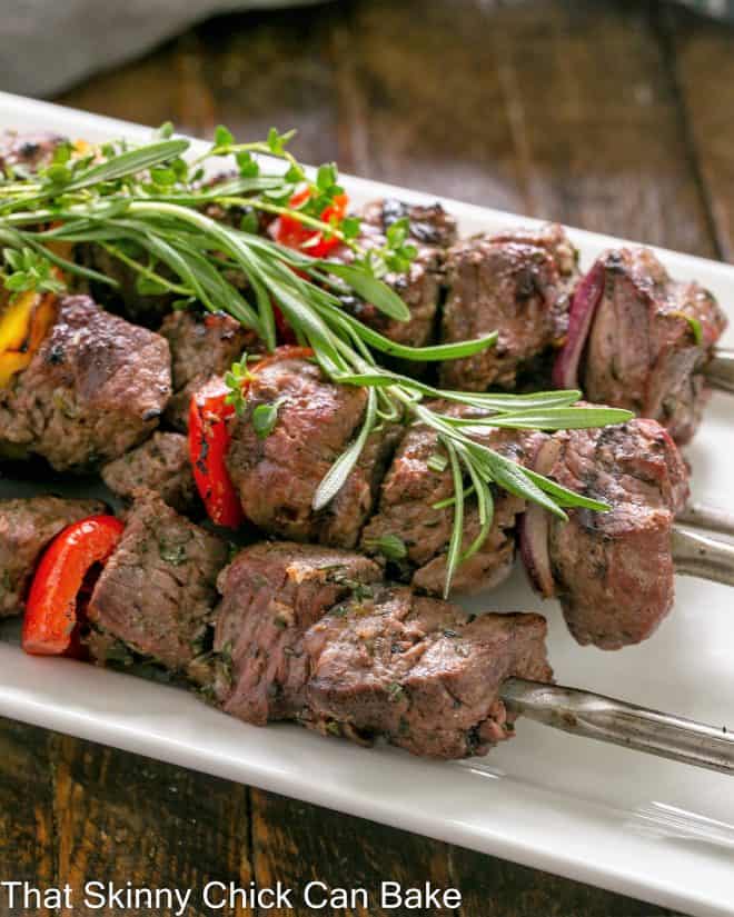 Close up of skewered lamb kebabs on a white serving tray